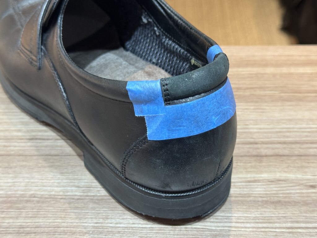 縫製前に履き口をマスキングテープで固定し、補修位置を整えた工程中の様子。