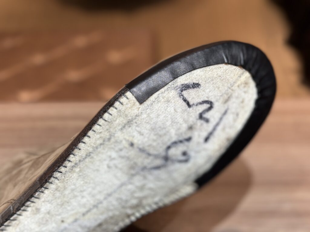 レザーテープでストローベル製法のステッチを覆っている途中工程の写真。