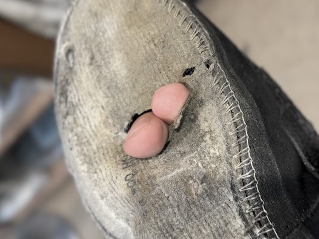 中底に穴が開いた状態のスエードローファー。指で押さえると貫通するほど摩耗しており、補修が必要な様子。