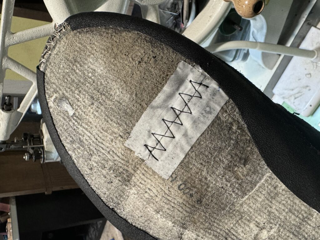 摩耗した中底を布で補強し、ミシンで縫い留めた様子。耐久性を高める補修作業の一環。