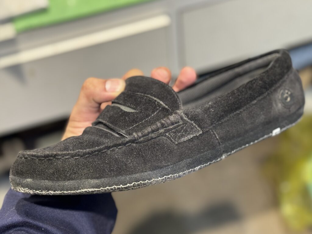 修理前の黒スエードローファー。アウトソールを外した状態で、アッパーの形を整えている様子。