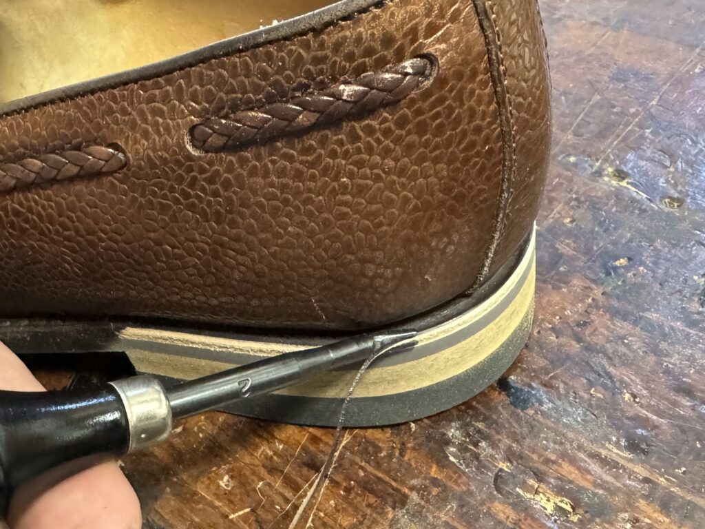 ヒール周りのバリを靴用工具で丁寧に落としている作業風景