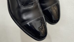 クロケット&ジョーンズの黒革靴、つま先に映り込む光沢が際立つ鏡面仕上げ。