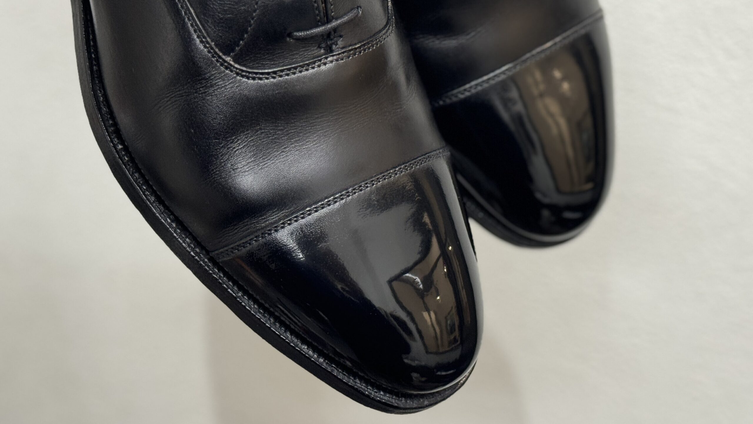 クロケット&ジョーンズの黒革靴、つま先に映り込む光沢が際立つ鏡面仕上げ。
