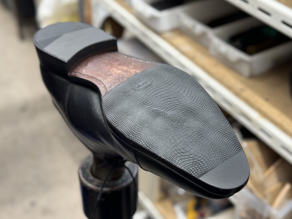 修理後の靴底を裏面から撮影した写真。継ぎ足し箇所が自然に馴染み、ソール全体が整った状態になっている