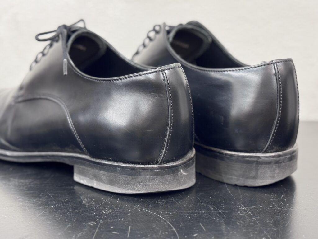 黒革の内羽根ストレートチップのかかと周りを後方から撮影した修理前の状態。