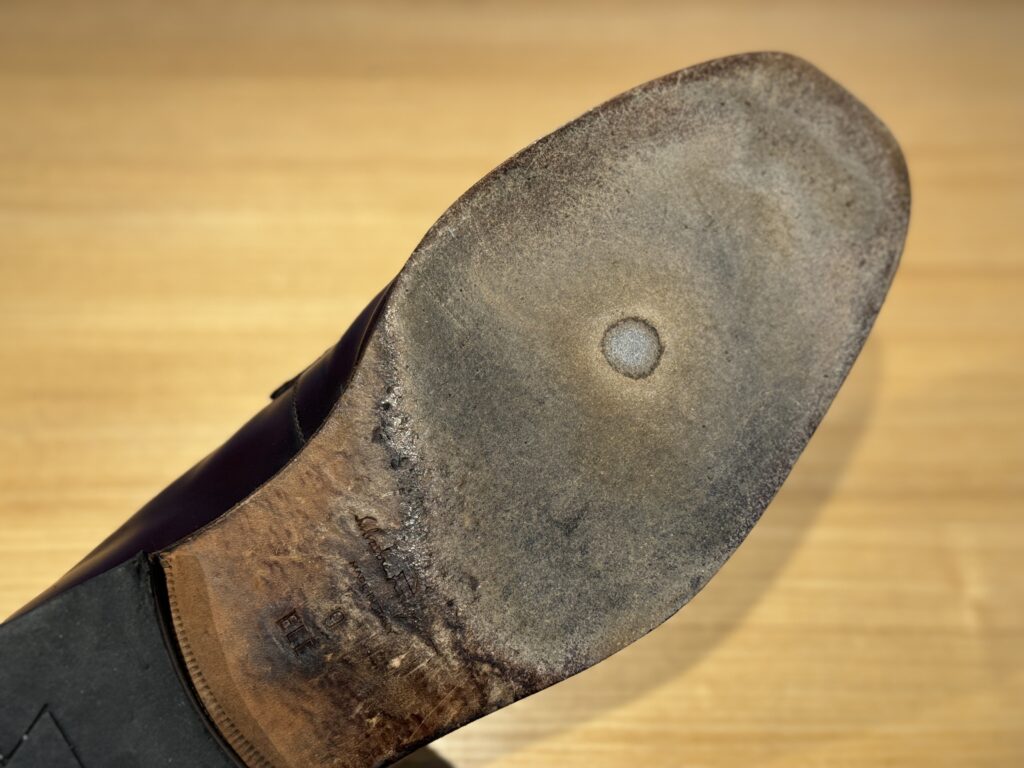 修理前のアウトソール。中央に穴が開き、レザーソールが大きく摩耗している。