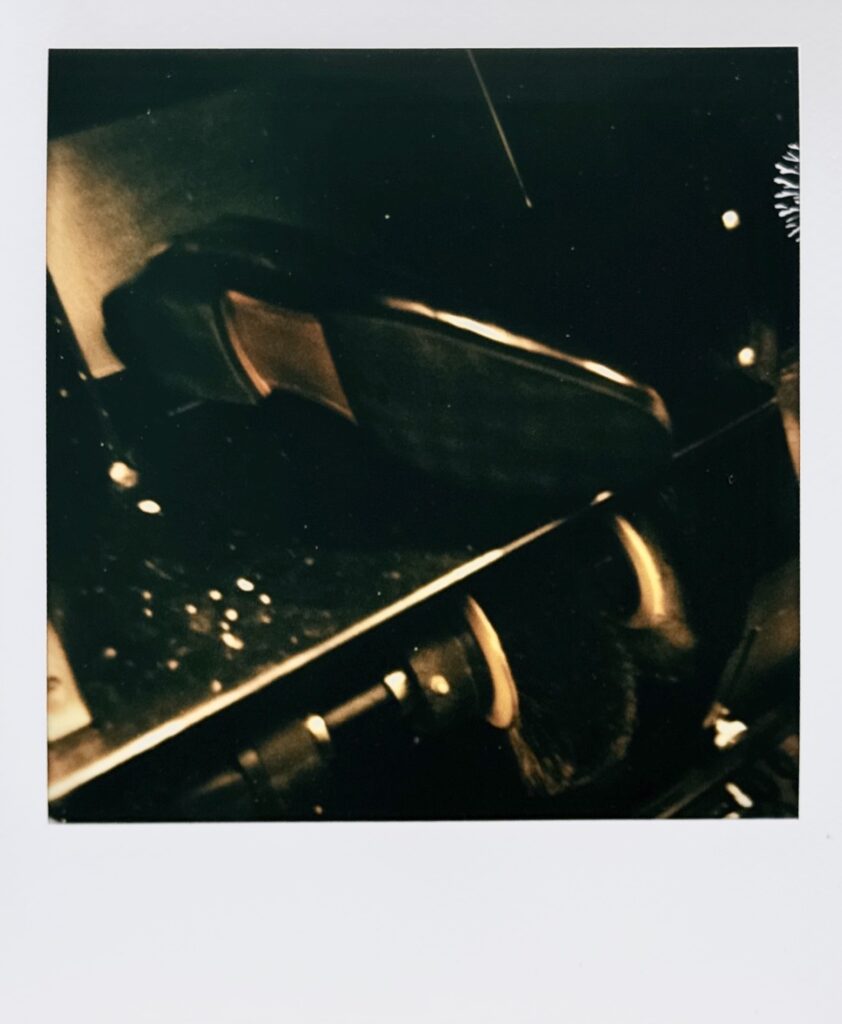 フィニッシャーの上に置かれた修理後ローファーを写したポラロイド。落ち着いた陰影の中で靴の存在感が浮かび上がる。