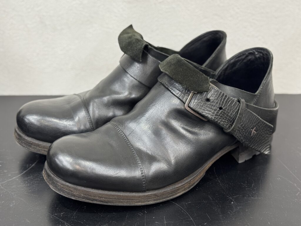 m.a+（エムエークロス）の修理前の全体像。バックルストラップ付きの黒レザーシューズ