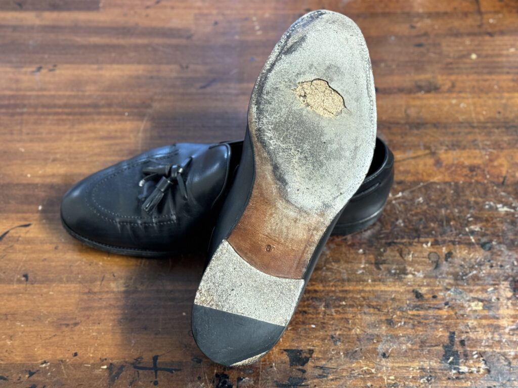 修理前のソールを裏面から撮影。穴あきと摩耗が進んだレザーソールの状態が分かる。