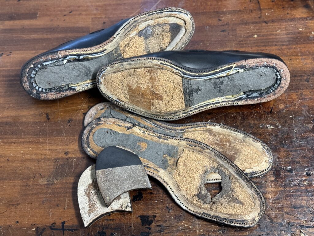 ソールを解体し、中物や縫いつけ跡が露出した状態。内部構造が見える工程途中の様子。