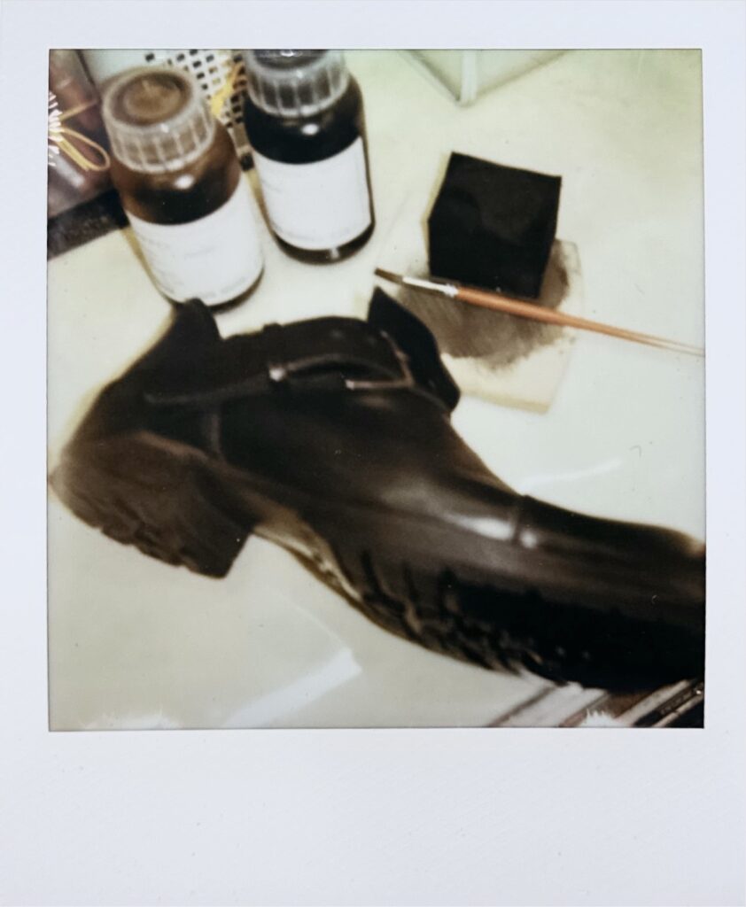 コバの染色剤を調色している様子。染料ボトルと筆、黒の溶液が写るポラロイド写真
