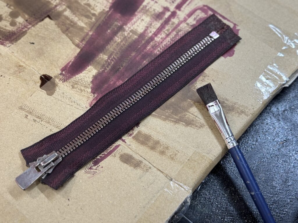 YKKエクセラファスナーを染色して色味を調整している工程（刷毛と染料跡）