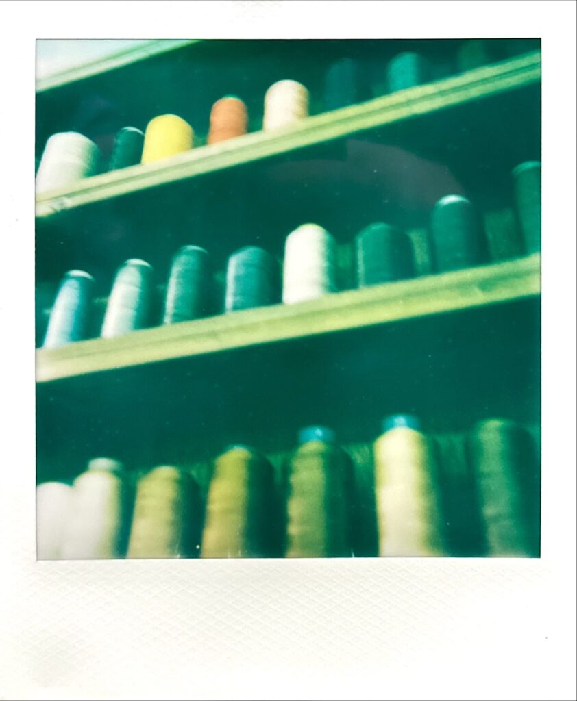 靴修理作業台に置かれたミシン糸をポラロイド調で撮影した写真。修理工程の余白を感じさせるカット